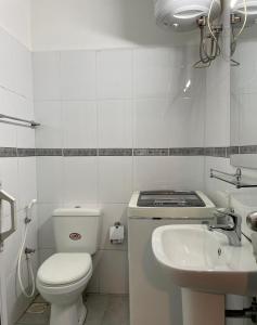 a white bathroom with a toilet and a sink at Breeze Holiday Casa in Nuwara Eliya