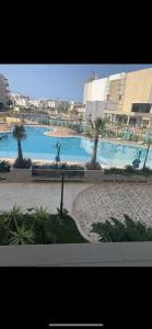 a large swimming pool with palm trees in front of a building at Appartement Résidence Palm Lake Monastir in Monastir