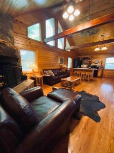 a living room with a leather couch and a fireplace at Chalet with a view at Bear Mountain - Hottub in Eureka Springs