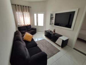 a living room with a couch and a flat screen tv at Ampla Casa em Aparecida in Aparecida