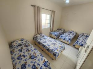 um quarto com quatro camas com lençóis azuis e brancos em Ampla Casa em Aparecida em Aparecida