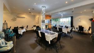un comedor con mesas y sillas blancas en Hilltop Motel, en Broken Hill