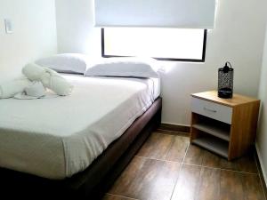 メデジンにあるApartamento en Medellín-clínica las Americasのベッドルーム1室(ベッド1台、白いベッド1台付きのナイトスタンド付)