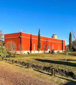 un gran edificio rojo con árboles delante de él en Casa en Haras Bettina, en Mercedes