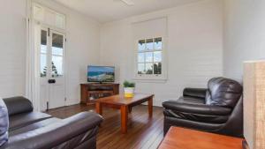 a living room with two leather chairs and a table at Reflections Yamba Lighthouse Cottages in Yamba