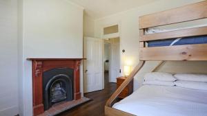 a bedroom with a bunk bed and a fireplace at Reflections Yamba Lighthouse Cottages in Yamba
