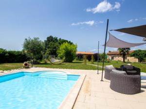 a swimming pool with two chairs and an umbrella at Gîte Marsac-sur-l'Isle, 2 pièces, 2 personnes - FR-1-616-244 in Marsac-sur-lʼIsle