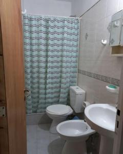 a bathroom with a toilet and a sink and a shower curtain at Departamento Plaza España in San Rafael