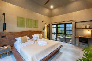 a bedroom with a large white bed and a bathroom at Zee Design Villa & Spa Sanur in Sanur