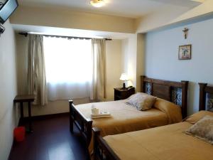a hotel room with two beds and a window at Hotel Maison Fiori Prado in Cochabamba