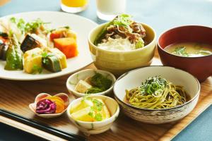 uma mesa com pratos e tigelas de comida em hotel MONday Kyoto Karasuma Nijo em Quioto