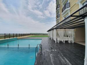 a swimming pool with white chairs and a building at A Modern & Homely Studio with Pool and Gym in Kampar