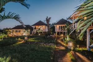 an image of a house at night with palm trees at Paluh Beach Huts in Nusa Lembongan