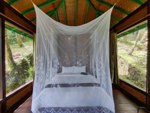 a bed in a room with a mosquito net at Rimba eco Resort in Tomohon