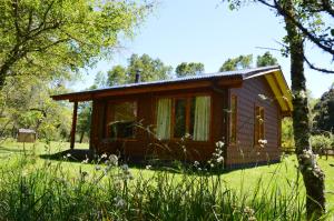 a small cabin in a field with trees and grass at Cabañas Valle del Río in Curacautín