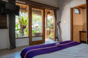 a bedroom with a bed and a large window at Village Vibes Lombok in Kuta Lombok