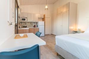a bedroom with a white bed and a kitchen at Costa Mare in Paralia Vrachou