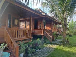 ein Holzhaus mit einer Veranda und einem Hof in der Unterkunft Pondok Elen Mandalika in Praya