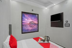 a room with a bed with a red pillow and a picture at OYO Flagship Kwins Residency in Ghaziabad