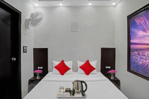 a bedroom with a white bed with red pillows at OYO Flagship Kwins Residency in Ghaziabad