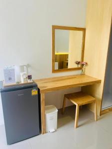 a small desk with a mirror and a small refrigerator at สราญรัตน์รีสอร์ท in Ban Noen Makok