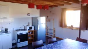 a kitchen with a refrigerator and a table with chairs at Aguas Claras del Sur in Dina Huapi