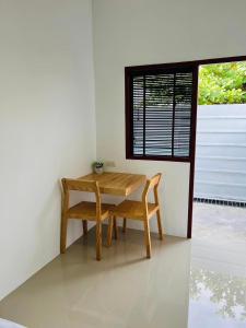 una mesa de madera y una silla en una habitación con ventana en สราญรัตน์รีสอร์ท en Ban Noen Makok