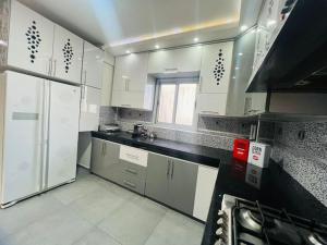 a kitchen with white cabinets and a black counter top at Calm Apartment in Mazola next to Aeria Mall & Casa Finance City in Casablanca