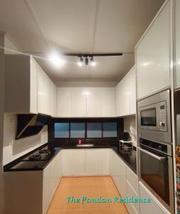 a kitchen with white cabinets and a microwave at The Pandan Residence in Kuantan