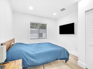 a bedroom with a blue bed and a television at Upscale 3 Bedroom House in Centric Location - in Miami Shores in Miami