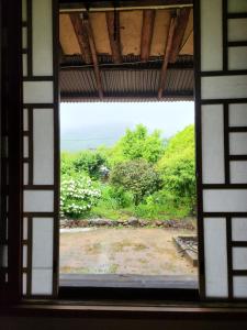 una ventana con vistas al jardín desde un edificio en Hanok Soeun House en Miryang