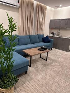 بارك المدينة للشقق المخدومة في المدينة المنورة: غرفة معيشة مع أريكة زرقاء وطاولة قهوة