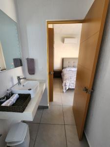 a bathroom with a sink and a toilet and a bed at Casa Minerva in Naranjo