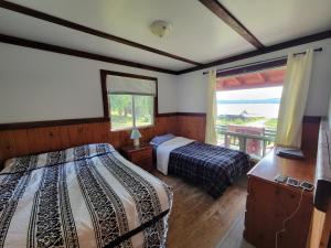 een slaapkamer met 2 bedden en een groot raam bij Chalet with great lake view in Gracefield