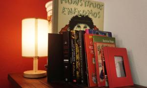 une pile de livres sur une table à côté d'une lampe dans l'établissement Habitacion Roja / Casa del Café, à Campeche