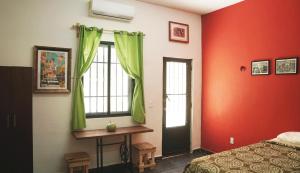a bedroom with red walls and a bed and a window at Habitacion Roja / Casa del Café in Campeche