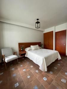 um quarto com uma cama grande e uma cadeira em Casa Sol em Oaxaca de Juárez