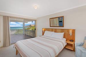 ポートランドにあるAbalone Beach Houseのベッドルーム1室(ベッド1台付)、海を望むバルコニーが備わります。