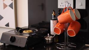 a kitchen counter with a stove with cups and a bottle of wine at El Hogar in Kiambu