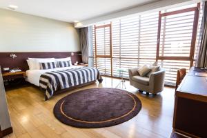 a bedroom with a bed and a chair and a large window at NOI Vitacura in Santiago