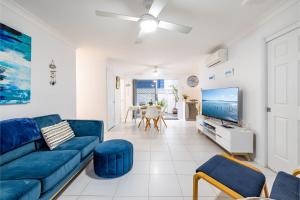 フィンガル・ベイにあるSapphire Sands 1 52 Boulder Bay Rd air con Wi Fi Cot and Highchairの青いソファとテレビのあるリビングルーム