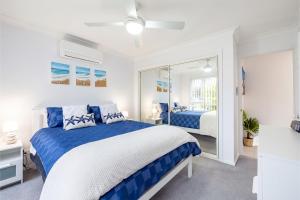 フィンガル・ベイにあるSapphire Sands 1 52 Boulder Bay Rd air con Wi Fi Cot and Highchairのベッドルーム(青と白のベッド、鏡付)