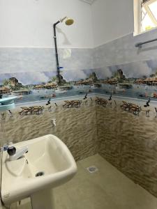 a bathroom with a sink and a mural of a beach at Vibushan Guest House in Nilaveli