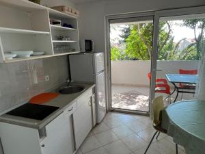 a kitchen with a sink and a counter with a table at Apartments MiaMaja in Novalja