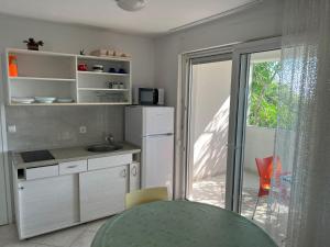 a kitchen with a sink and a door to a patio at Apartments MiaMaja in Novalja