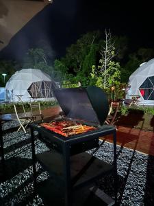 a bbq grill with two tents in the background at The Dome @ Gua Musang in Gua Musang