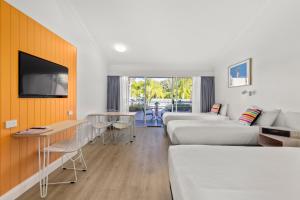 a hotel room with two beds and a flat screen tv at The Cubana Resort Nambucca Heads in Nambucca Heads