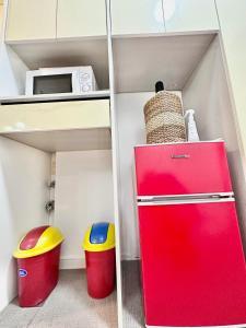 a red refrigerator in a kitchen with two trash cans at 3 Smart Condominium in Cagayan de Oro City in Cagayan de Oro