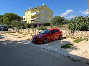 a red car parked in front of a building at Apartments MiaMaja in Novalja