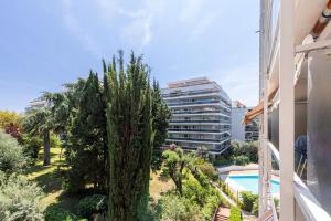 een balkon met uitzicht op een gebouw en een boom bij Appartement 6 couchages dans résidence avec piscine in Juan-les-Pins